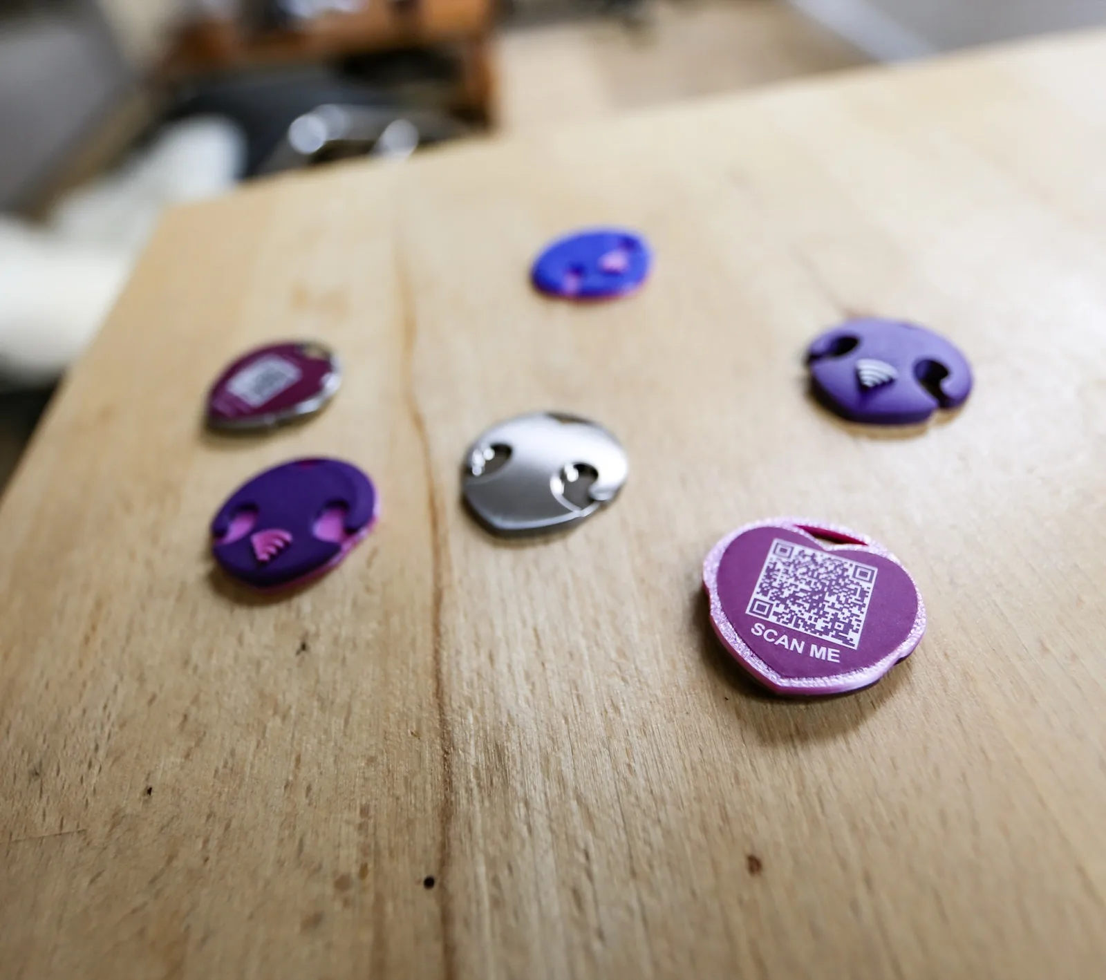 pacjent.vet-Tiermarken auf einem Holztisch — bunte NFC-Anhänger und ein Stahlherz mit QR-Code